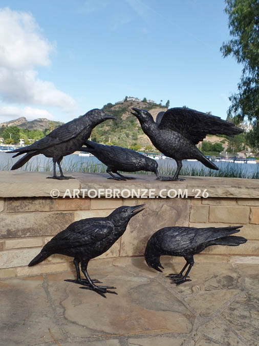 Raven bronze statues of ravens playing on bench at lake
