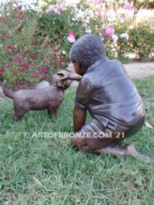 Scrappy bronze garden sculpture of boy playing with his dog