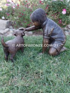 Scrappy bronze garden sculpture of boy playing with his dog