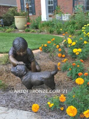 Scrappy bronze garden sculpture of boy playing with his dog