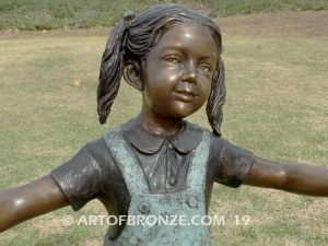 Sing Along wonderful outdoor bronze sculpture featuring three young kids holding hands and dancing