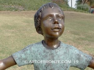 Sing Along wonderful outdoor bronze sculpture featuring three young kids holding hands and dancing