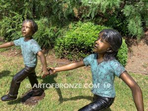 Sing Along wonderful outdoor bronze sculpture featuring three young kids holding hands and dancing