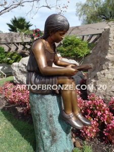 Study Time bronze sculpture of young reader girl sitting on bronze stump