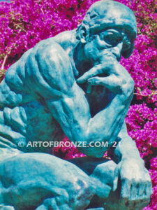 Famous bronze sculpture The Thinker monument nude seated on a rock, chin resting on his hand
