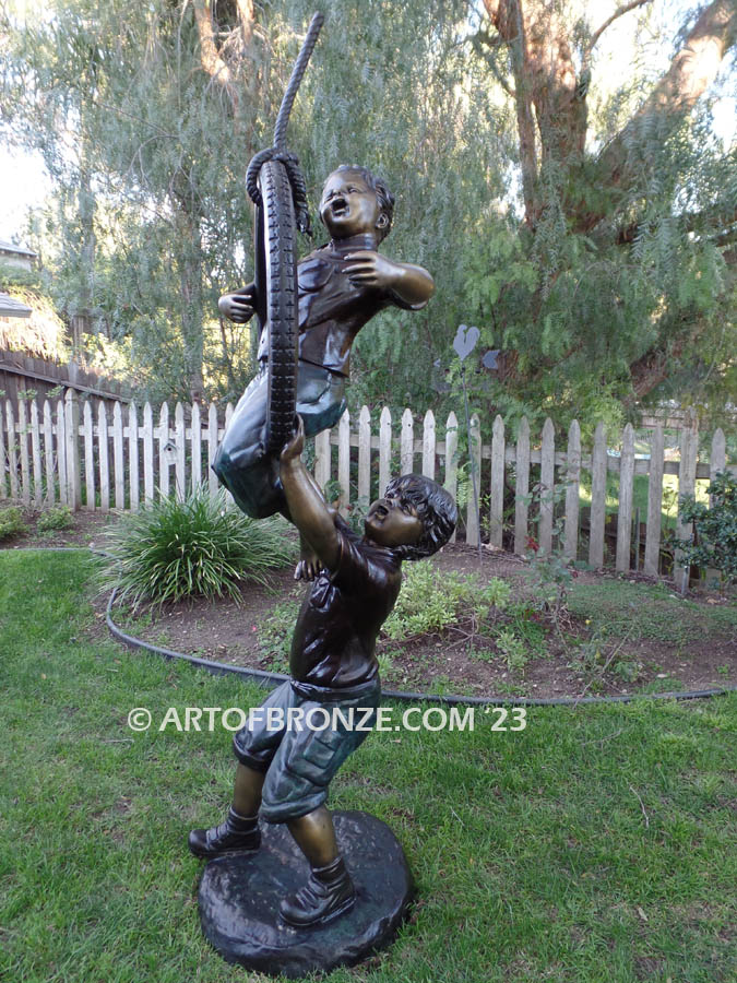 tire swing children bronze sculpture two boys playing together