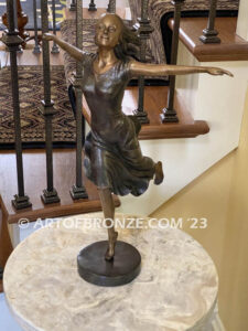 Wind Swept bronze statue joyous woman gracefully balancing on one foot