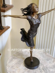 Wind Swept bronze statue joyous woman gracefully balancing on one foot