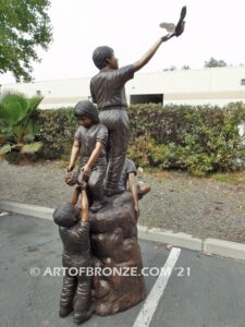 High Hopes bronze sculpture of four children playing on bronze rock for park or school playground
