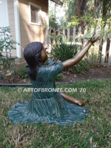 Wings of Joy bronze statue of sitting girl with butterflies on her dress and hand