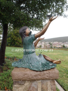 Wings of Joy bronze statue of sitting girl with butterflies on her dress and hand