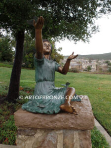 Wings of Joy bronze statue of sitting girl with butterflies on her dress and hand