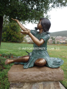 Wings of Joy bronze statue of sitting girl with butterflies on her dress and hand