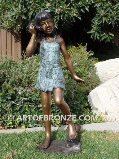 Captivating bronze fountain statue of girl standing listening to seashell