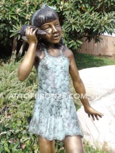 Captivating bronze fountain statue of girl standing listening to seashell