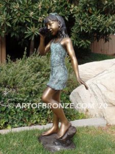 Captivating bronze fountain statue of girl standing listening to seashell