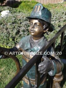 Junior Fireman bronze sculpture of firefighter boy wearing helmet and turnout coat