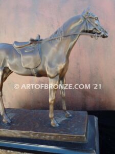 Saddled sculpture of standing horse with saddle and tack attached to base for indoor home or office