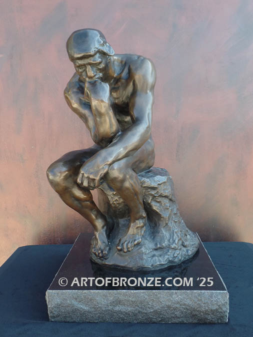 Famous bronze sculpture The Thinker monument nude seated on a rock, chin resting on his hand