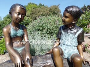 Telling Stories wonderful outdoor bronze sculpture featuring three children playing together on bronze log