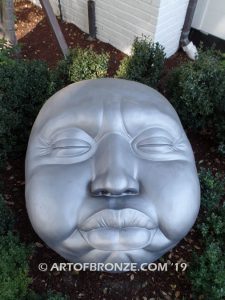 Expression sculpture of massive bronze face for outdoor and garden display