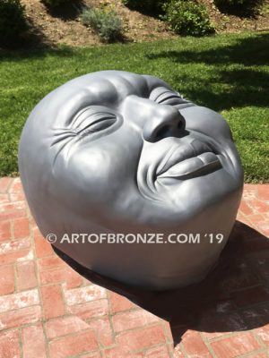 Expression sculpture of massive bronze face for outdoor and garden display