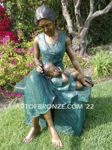 Mothers Love bronze sculpture of seated woman sitting on bench with young boy sleeping on her lap