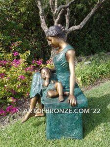 Mothers Love bronze sculpture of seated woman sitting on bench with young boy sleeping on her lap