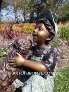 Best Buddies bronze sculpture of young boy petting his dog on his lap