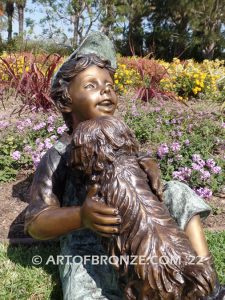 Best Buddies bronze sculpture of young boy petting his dog on his lap