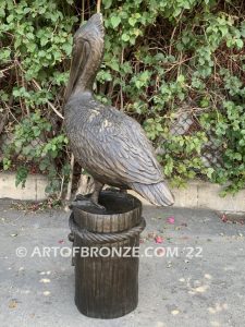 Home Pier bronze statue of playful pelican on bronze piling with rope