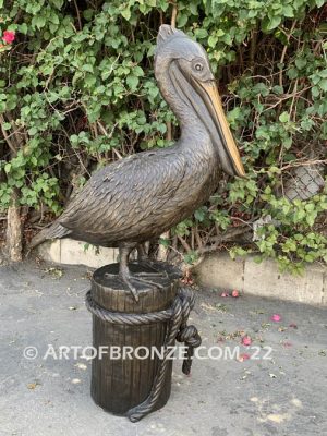 Home Pier bronze statue of playful pelican on bronze piling with rope
