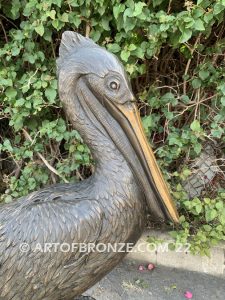 Home Pier bronze statue of playful pelican on bronze piling with rope