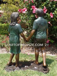 Taking a Stroll outdoor bronze sculpture brother and sister walking together holding hands