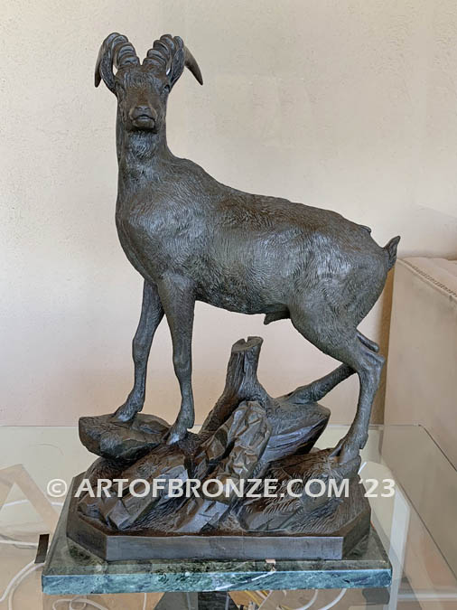 Ibex bronze sculpture standing on rocky base with large horns and rich texturing