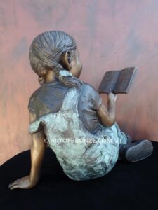 Book Smart bronze sculpture of seated girl reading book with smiling expression