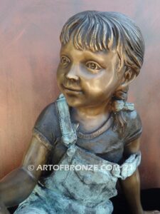 Book Smart bronze sculpture of seated girl reading book with smiling expression
