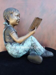 Book Smart bronze sculpture of seated girl reading book with smiling expression