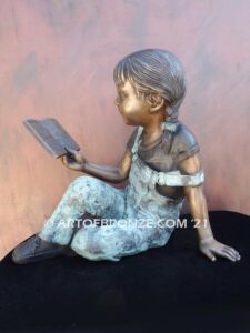 Book Smart bronze sculpture of seated girl reading book with smiling expression