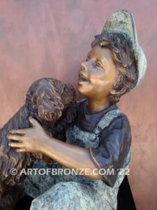 Best Buddies bronze sculpture of young boy petting his dog on his lap