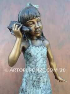 Captivating bronze fountain statue of girl standing listening to seashell