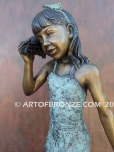 Captivating bronze fountain statue of girl standing listening to seashell