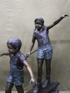 Day of Adventure bronze sculpture of two children and dog strolling across bronze log