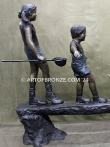 Day of Adventure bronze sculpture of two children and dog strolling across bronze log