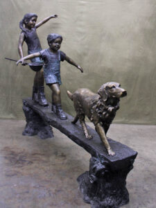 Day of Adventure bronze sculpture of two children and dog strolling across bronze log