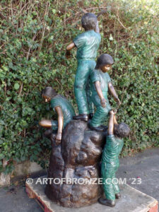 High Hopes bronze sculpture of four children playing on bronze rock for park or school playground