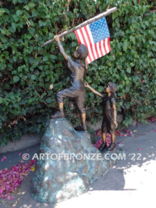 Raising Glory outdoor bronze garden sculpture of two children raising flag