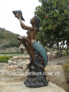 Bronze mermaid sea goddess statue swimming with dolphins holding shell for pond, pool or aquatic display