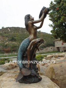 Bronze mermaid sea goddess statue swimming with dolphins holding shell for pond, pool or aquatic display