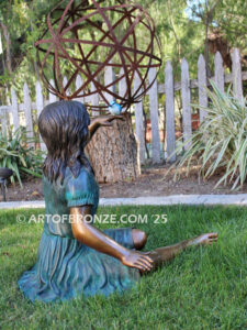 Wings of Joy bronze sculpture of sitting girl in dress with bronze bird perched on her hand